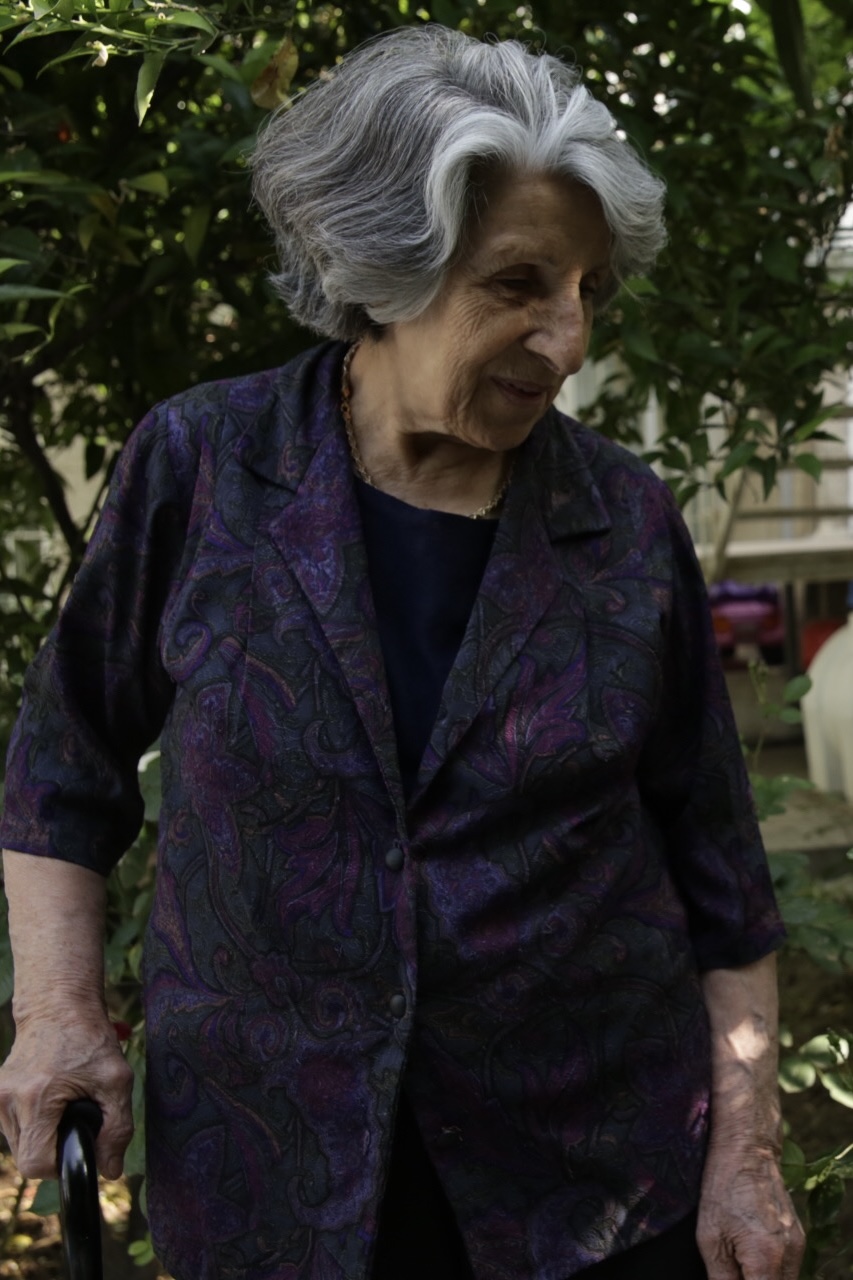 Caregiver helping elderly man walk in park